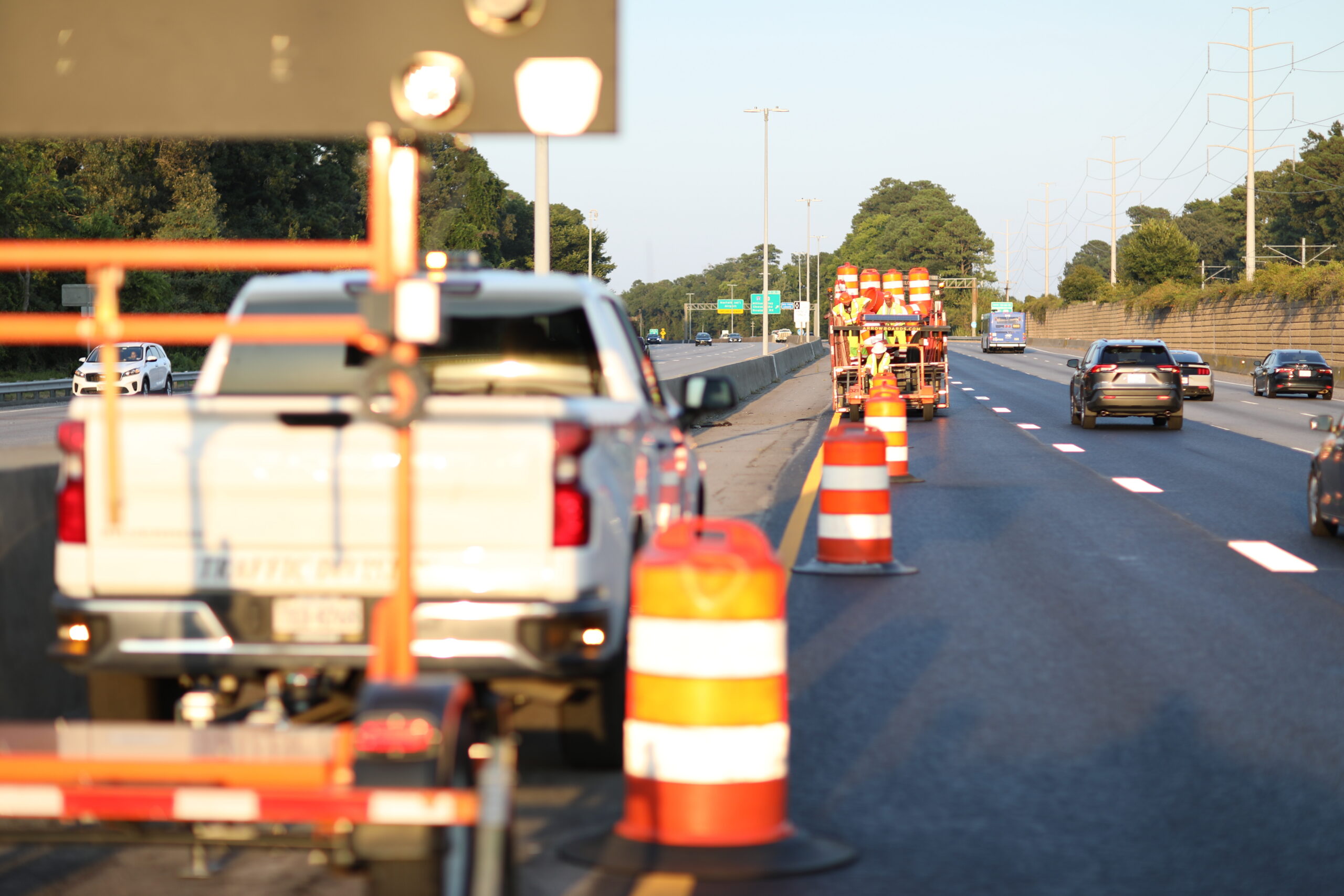 Traffic control equipment including cones, barricades, warning signs, and an arrow board truck used on a construction work zone roadway