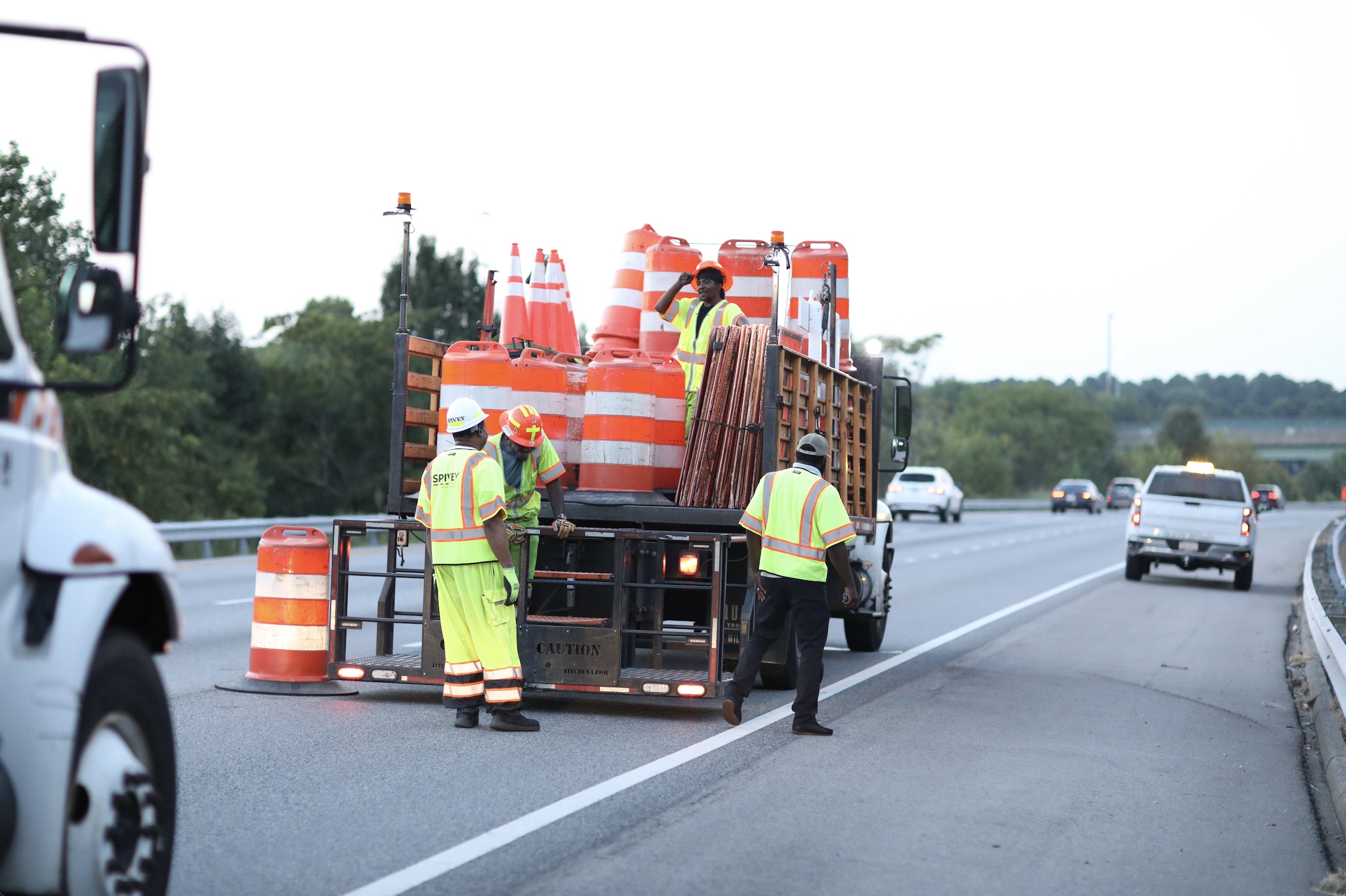 Traffic control crew setting up barriers and cones on a roadway, ensuring safety during construction in Virginia, with Spivey Services branding visible on uniforms.