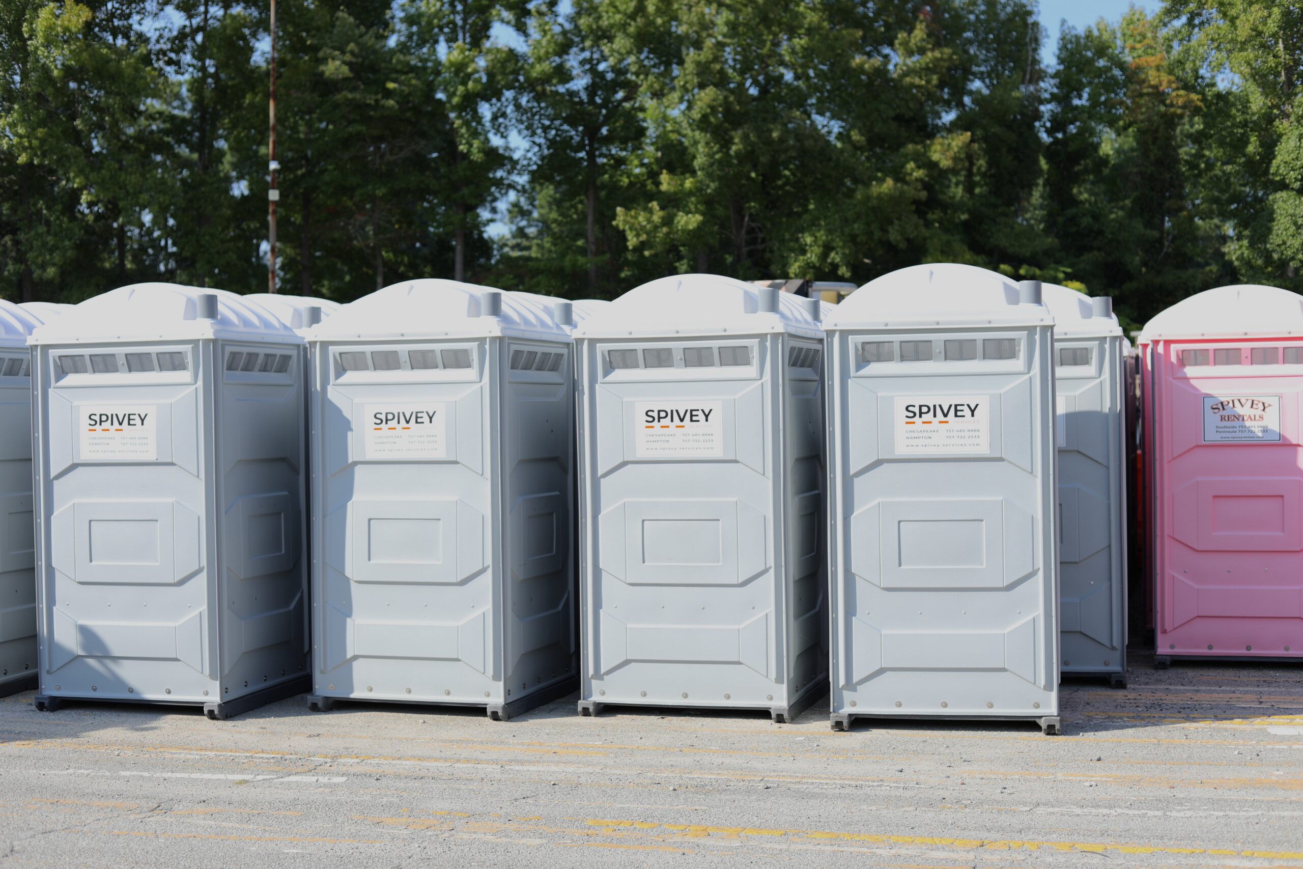 Portable toilets lined up for rental by Spivey Services in Richmond, VA, showcasing sanitation solutions for events and construction sites.