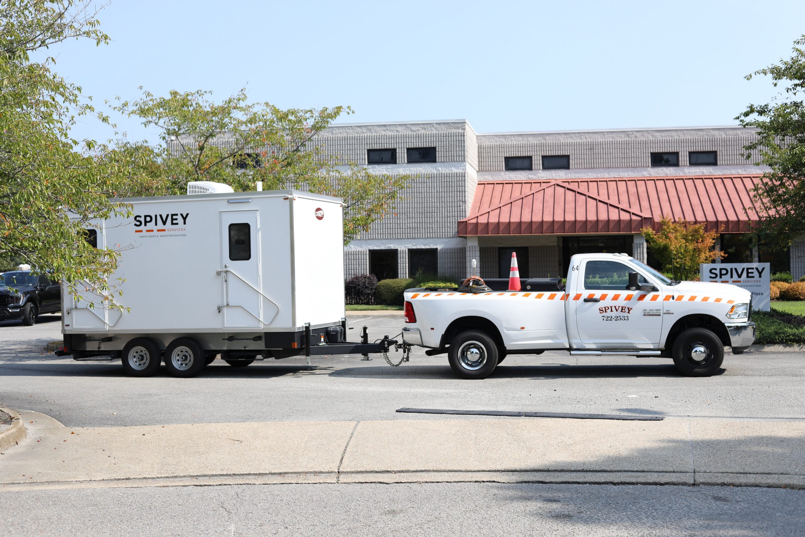 restroom trailer rental Chesapeake VA being towed by Spivey Services-branded truck